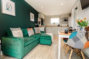a living room with a green couch and a kitchen at Beth's Bothy in Gatehouse of Fleet