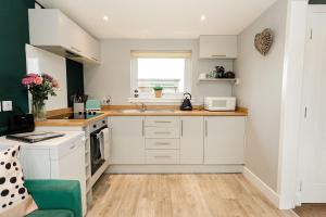 a kitchen with white cabinets and a green chair at Beth's Bothy in Gatehouse of Fleet +44 photos