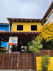 a yellow house with a sign in front of it at Pousada Maia in Itaúnas