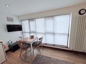 a dining room with a table and chairs and a large window at Millbrook House Apartments 9 in Milton