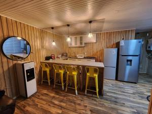 a kitchen with yellow bar stools and a refrigerator at Loft playaBlanca in Coronel