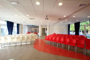 una sala de conferencias con sillas rojas y sillas blancas en Club Village & Hotel Spiaggia Romea, en Lido di Volano
