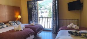 two beds in a hotel room with a large window at Hotel Saurat in Espot +74 photos