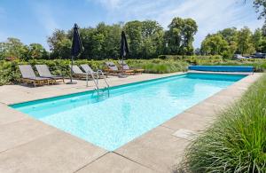 a swimming pool with chairs and umbrellas in a yard at De Kasteelboerderij in Ruurlo