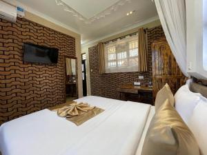 a bedroom with a white bed and a tv on a wall at Mawimbi Jiko Hotel in Taveta