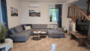 a living room with a couch and a tv at Villa Prima Wellness Badacsony in Badacsonytomaj