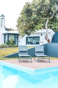 two chairs sitting next to a swimming pool at Casa da Vila Apartments in Arco da Calheta