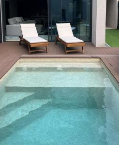 a swimming pool with two lounge chairs next to a house at Fine Arts in Moledo