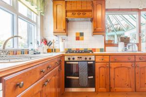 a kitchen with wooden cabinets and a stove top oven at Stoneywell Cottage - Elie in Elie