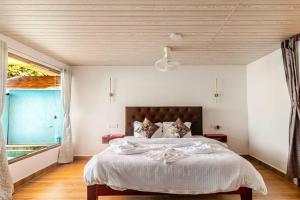 a bedroom with a large bed with a large window at Sea Shades Cottages with Private Jacuzzi in Palolem