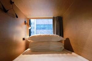 a bedroom with a bed with pillows and a window at L YOUNG Inn Capsule Hotel Myeongdong in Seoul +13 photos