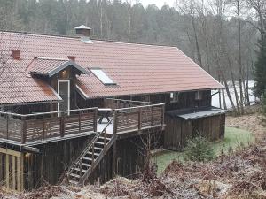 a large wooden house with a deck and a roof at Annexet Hjälmareds mill in Alingsås