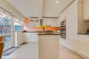 a kitchen with white cabinets and orange walls at The Sweet Spot in Ickenham +7 photos