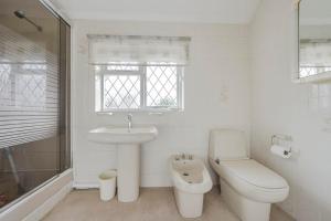 a white bathroom with a toilet and a sink at The Sweet Spot in Ickenham