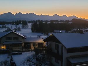 a house in the snow with mountains in the background at Ferienwohnung Obstgarten in Halblech
