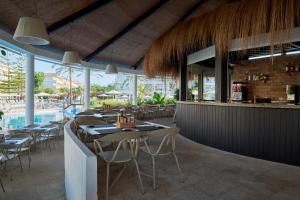 a restaurant with tables and chairs and a pool at Prinsotel La Dorada & Spa in Playa de Muro