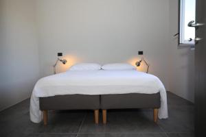 ein Bett mit weißen Laken und Kissen in der Unterkunft C A S A A D E L E per una vacanza in semplicità e relax in Itri