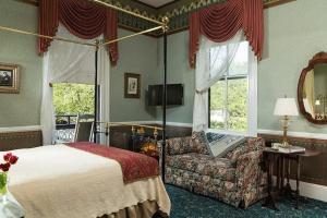 a bedroom with a bed and a chair and a mirror at The Queen Victoria in Cape May