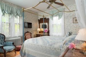 a bedroom with a canopy bed and a blue chair at The Queen Victoria in Cape May