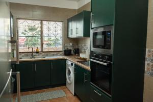 a kitchen with green cabinets and a window at T3 Elegance x Nawassi Moderne, climatisé, sécure in Pamandzi