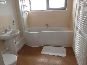 a bathroom with a tub and a sink and a toilet at Elegant three bedroom flat in Darlington +17 photos