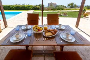 a table with a bowl of fruit and a plate of bread at Chios Seafront Luxury Villa with Pool in Chios