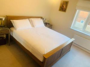 a bedroom with a large bed with white sheets and a window at GR8 Home in Kingsley