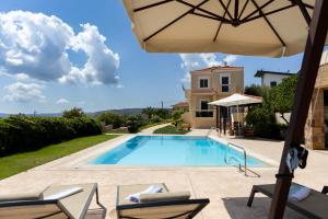 a villa with a swimming pool and an umbrella at Chios Seafront Luxury Villa with Pool in Chios