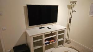 a flat screen tv sitting on top of a white cabinet at Lillstugan i Rasbo in Uppsala +21 photos