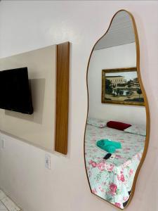 a mirror on a wall with a bed and a television at Apartamento no Centro in Manaus