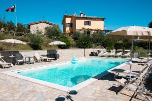 a swimming pool with chairs and umbrellas and a house at Agriturismo La Coccinella in Valfabbrica