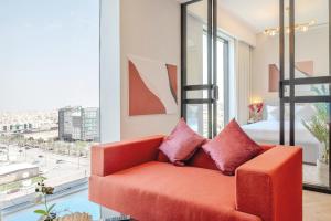 a living room with a red couch and a large window at Stella Stays King Fahd - Furnished Apartments in Riyadh