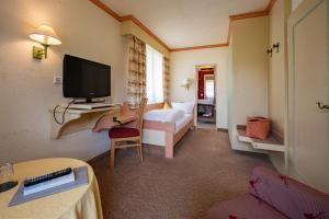 a hotel room with a television and a bedroom at Hotel Lamm Baiersbronn Mitteltal in Baiersbronn