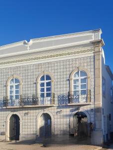 a large brick building with windows and a balcony at Apartamentos do Rio in Tavira