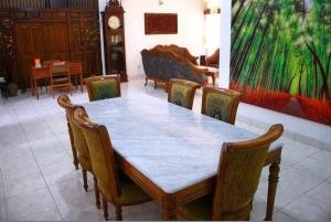 a dining room table with chairs and a clock in the background at Guest House Pogung Baru in Yogyakarta