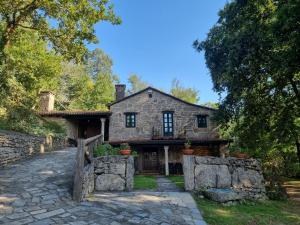an old stone house with a stone driveway at A Regueira Habitaciones in Alján