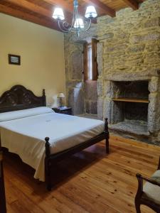 a bedroom with a bed and a stone fireplace at A Regueira Habitaciones in Alján +28 photos