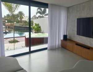 a living room with a tv and a large window at Angra casa in Angra dos Reis
