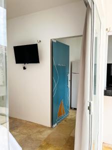 a room with a sliding door with a tv on a wall at Pousada Vila Didi - Flats com Cozinha Completa in Barra Grande