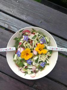 a bowl of salad with flowers on a wooden table at Pension Fernsicht in Außerteuchen +25 photos