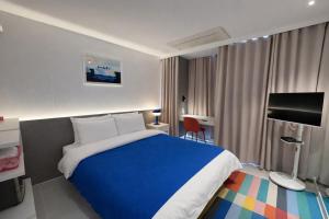 a hotel room with a blue bed and a desk at 제주 디스피어 호텔 D-Sphere in Jeju