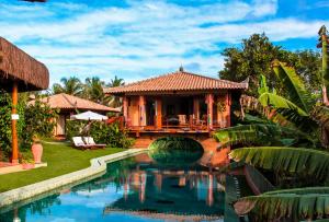 uma villa com piscina em frente a uma casa em Sagui Boutique Hotel em Arraial d'Ajuda