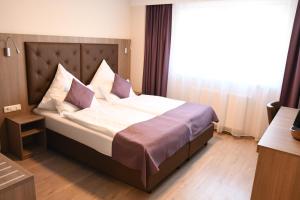 a bed in a hotel room with a large window at Ata Hotel - Self Check-in in Hamburg