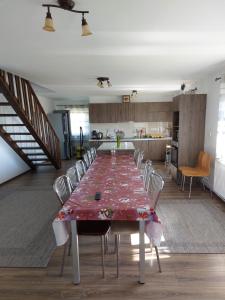a large dining room table with chairs and a kitchen at Sári Vendégház in Remetea