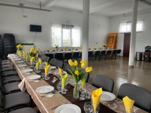 a long table with yellow flowers in a room at Sári Vendégház in Remetea