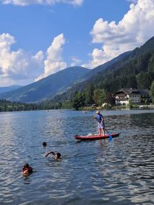 a person standing on a paddle board in a lake at Pension Fernsicht in Außerteuchen