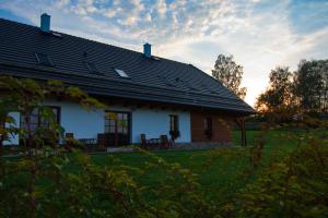 a white house with a black roof in a field at Chalupa Pod Šerovnou in Prachatice