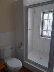 a bathroom with a toilet and a glass shower at De Kothuize 4 in Graaff-Reinet