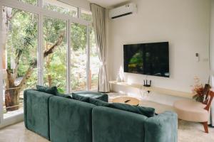 a living room with a green couch and a large window at Mooncake house khaoyai in Ban Bung Toei