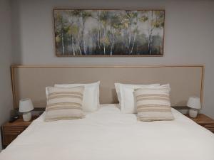 a bed with white pillows and a painting above it at Kinn Accommodation in Bloemfontein